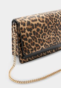 Torebka typu kopertówka w panterkę z złotym łańcuszkiem, czarnymi akcentami i błyszczącym metalowym logo. Wykonana z teksturowanego materiału syntetycznego.