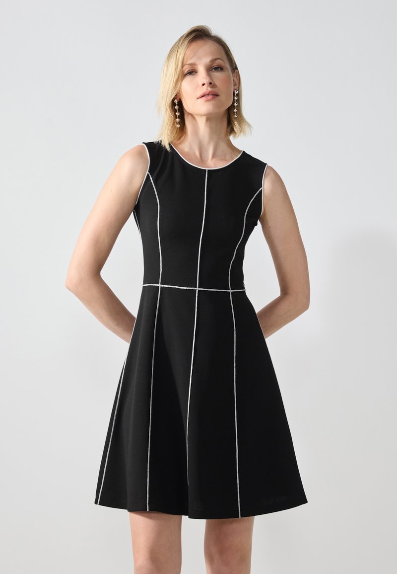 Musthave mustrõhu dress, millel on valged õmblused, sobituv korpus ja laienev seelik. Omab ümmargust kaelust ja sujuvat, tekstuurset kangast.