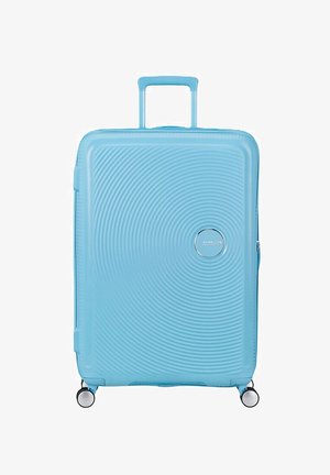 Valigia rigida azzurro chiaro con motivo a cerchi concentrici testurizzati, manico retrattile e quattro ruote girevoli.