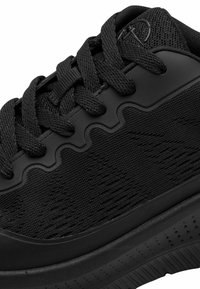 Chaussure de sport noire avec une tige en tissu texturé, une semelle en caoutchouc épaisse et des accents de design ondulés. Présente des lacets noirs et un col rembourré.