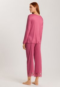 Långärmad pyjamasset med rund hals i rosa tyg; har spetsdetaljer vid byxans fållar; slät textur och avslappnad passform.