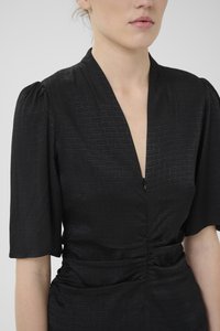 Black dress featuring a deep V-neck, gathered waist, short puff sleeves, and textured fabric with a subtle pattern.