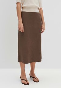 Gonna midi in suede marrone con forma dritta e cuciture sottili. Abbinata a sandali flip-flop neri per un look casual.