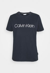 Námořnická modrá bavlněná tričko s kulatým výstřihem, krátkými rukávy a bílým logem "Calvin Klein" potisknutým na hrudi.