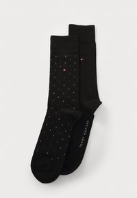 Chaussettes noires avec un motif texturé, l'une ornée de pois multicolores et l'autre unie, étiquetées "Tommy Hilfiger."