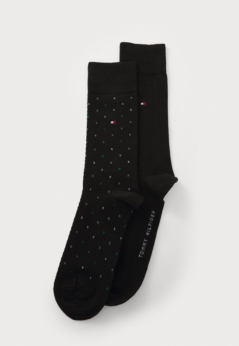 Chaussettes noires avec un motif texturé, l'une ornée de pois multicolores et l'autre unie, étiquetées "Tommy Hilfiger."