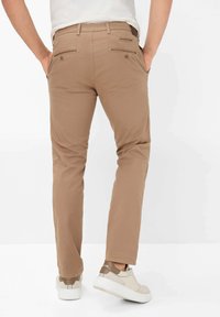 Tan katoen broeken met een rechte snit, voorzien van twee achterzakken met knopen en gecombineerd met witte en beige sneakers.
