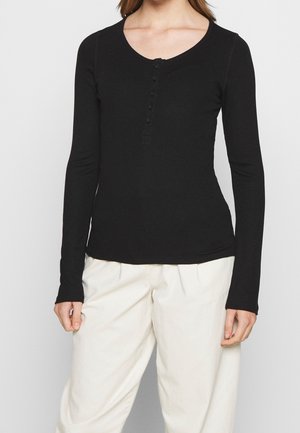 Black long-sleeve shirt with a scooped neckline and six-button placket. Made from ribbed material, fitted at the waist, and slightly curved hem.