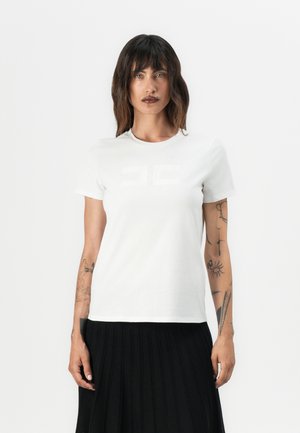 White cotton t-shirt with crew neck and short sleeves, featuring a subtle embossed design on the front, paired with a black pleated skirt.