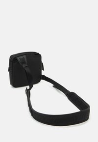 Borsa a tracolla nera con esterno liscio e imbottito, chiusura con zip e tracolla regolabile che presenta una sezione in rete per il comfort.