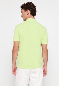 Polo shirt in felgroen, gemaakt van lichtgewicht katoen met een kraag en korte mouwen. Gladde textuur, eenvoudig ontwerp.