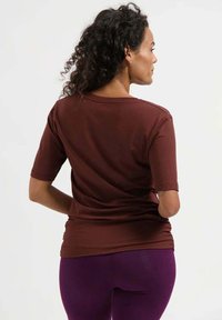 Bruin T-shirt met korte mouwen en een losse pasvorm, voorzien van een ronde hals en een zachte textuur, gecombineerd met paarse legging.