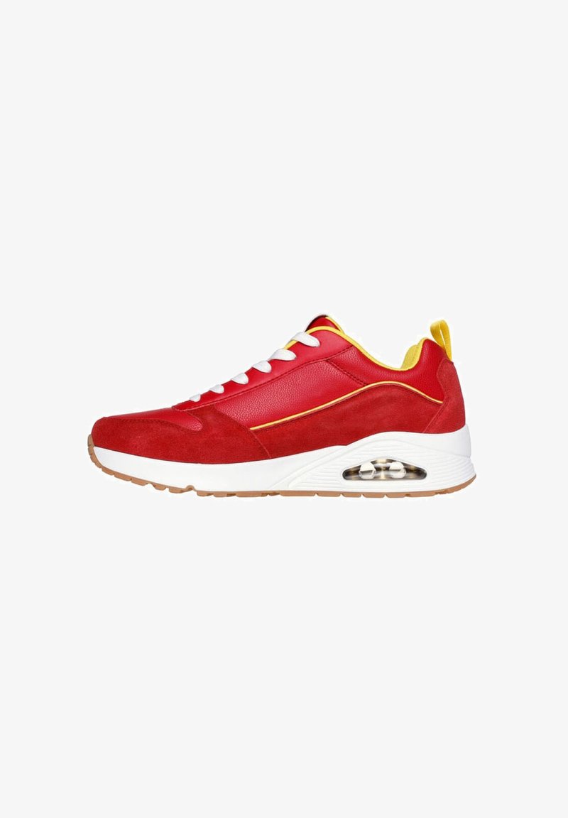 Red sneaker with suede and leather upper, white accents, rubber sole, and visible air cushioning. Features lace-up closure and yellow details.