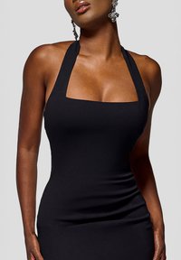 Sort ærmeløs bodycon-kjole med firkantet udskæring. Glat, strækbart stof fremhæver kroppen med en tætsiddende pasform og minimal detaljer.