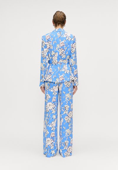 Blomstermønstret blå dragt med en skræddersyet blazer og vide ben. Har en indsnævret talje og mønstret stof med pastelnuancer.