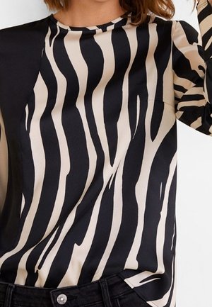 Satinoberteil mit einem schwarz-beigen Zebra-Streifenmuster, langen Ärmeln und einem Rundhalsausschnitt. Der Stoff hat eine glatte, glänzende Textur.