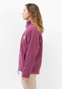 Lila Fleecejacke mit hohem Kragen, Seitentaschen und einer Brusttasche. Strukturiertes Material und verstellbarer Saum.