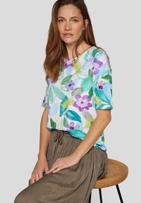 Short-sleeve floral top featuring a white background, colorful leaves and purple flowers, paired with a brown pleated skirt.