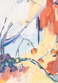 Lähikuva kankaasta, jossa on monivärinen abstrakti kukkakuosi, jossa on oransseja kukkia, sinisiä ja purppuraisia siveltimenvetoja sekä beige nappi.