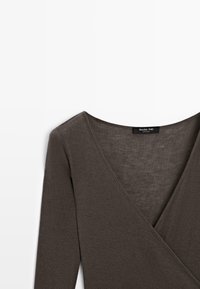 Top lungo a maniche con scollo a V marrone, realizzato in tessuto leggero e morbido con una texture liscia. Presenta un design pulito e minimale e un'etichetta.