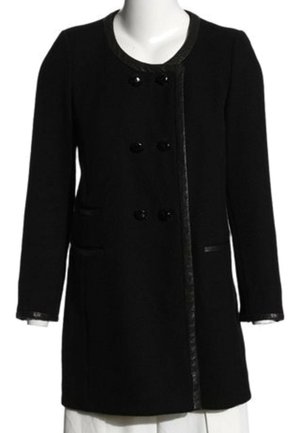 Manteau noir à manches longues avec six boutons sur le devant, col rond et deux poches latérales, porté par-dessus un vêtement blanc.