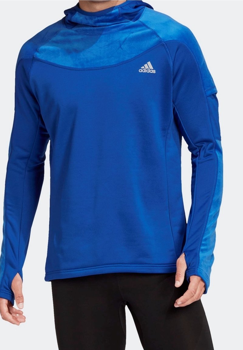 Maglia sportiva a maniche lunghe blu con cappuccio, caratterizzata da una texture liscia e un pannello a contrasto sulle spalle. Logo Adidas sul petto.