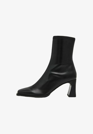 Stivale alla caviglia in pelle nera con punta affusolata, vestibilità aderente e tacco quadrato con un accento metallico. Texture liscia con dettagli minimi.