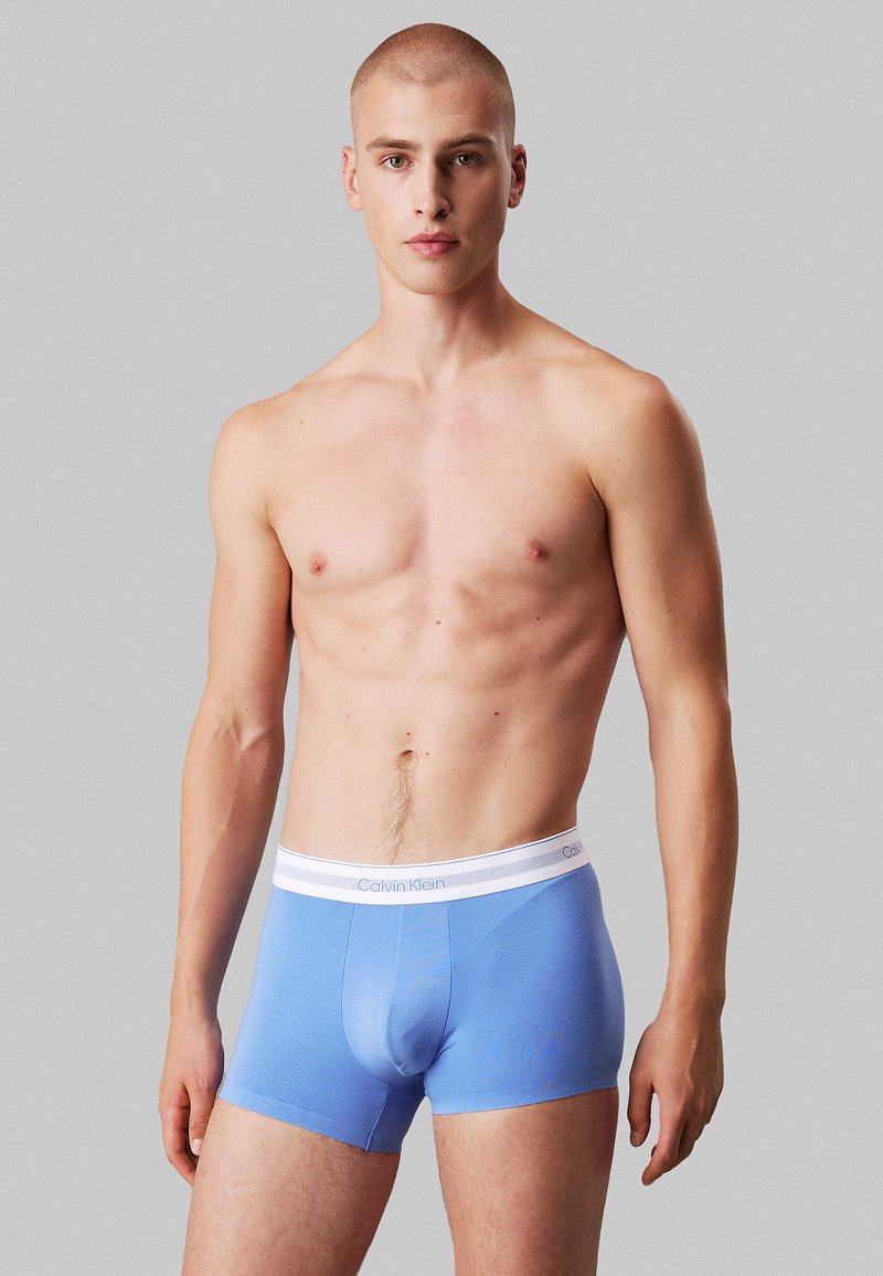 Boxer aderenti blu realizzati in morbido tessuto con elastico bianco che presenta il logo Calvin Klein. Design semplice e forma aderente.