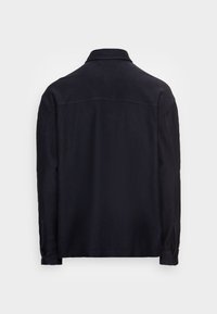 Giacca nera a maniche lunghe con colletto e polsini abbottonati, mostrata di spalle su uno sfondo bianco semplice.