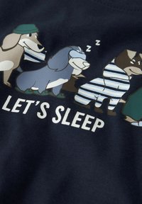 Tumed sinine T-särk, millel on koomiksikoerad pyžamades ja sildiga "LÄHEME MAGAMA". Koerad kannavad erinevaid aksessuaare ja mustreid.