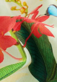 Blommig tyg med livfulla röda blommor och gröna blad mot en ljus bakgrund, med intrikata detaljer och en mjuk, slät textur.