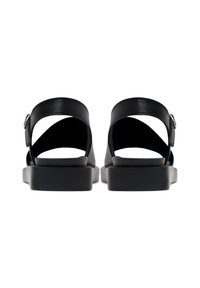 Sandale negre cu un superior din piele netedă, cataramă ajustabilă și o talpă groasă, joasă. Cu călcâi deschis și curele pentru gleznă. Design minimalist.