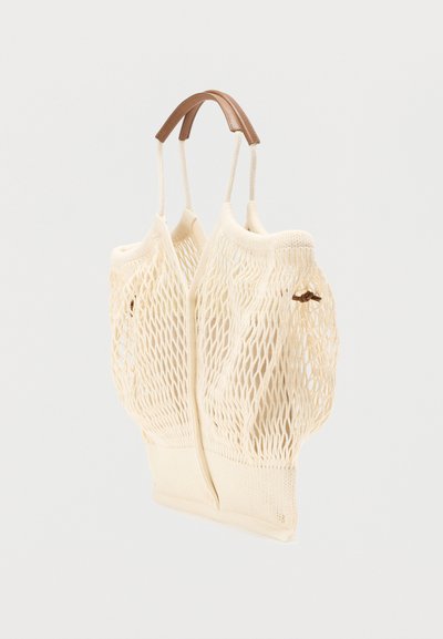 Τσάντα ώμου από δίχτυ σε κρεμ χρώμα με δύο μαλακές δερμάτινες λαβές, με σταθερή βάση και ανοιχτό πάνω μέρος για ευέλικτες επιλογές αποθήκευσης.