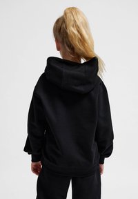 Schwarzer Kapuzenpullover mit einer großen Kapuze, Rippbündchen und Saum sowie einer lockeren Passform. Der Stoff wirkt weich und strukturiert, ideal für legere Anlässe.