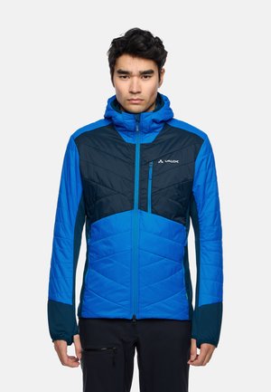 Blauwe geïsoleerde jas met een capuchon, een chevronpatroon, contrasterende donkere mouwen en een ritsvak op de borst. Lichtgewicht en waterafstotend.