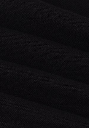 Close-up van zwart gebreid stof met fijne, gelijkmatige stiksels en een zachte textuur met zachte vouwen.