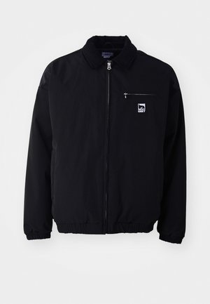 Schwarze Bomberjacke mit einem Cordkragen, Reißverschluss vorne, elastischen Bündchen und Saum; mit kleiner Brusttasche und einem Logopatch.