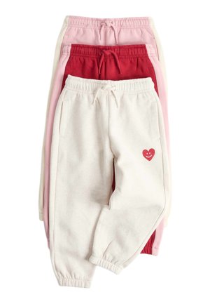 Tre sammenlagte joggingbukser i creme, rød og pink, med elastiske linninger og et lille rødt smilende hjerte på cremeparret.