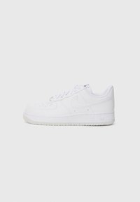Sneaker Nike Air Force 1 bianchi a basse, con punta perforata, chiusura con lacci e suola in gomma su uno sfondo chiaro.