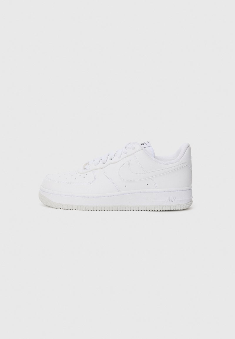 Sneaker Nike Air Force 1 bianchi a basse, con punta perforata, chiusura con lacci e suola in gomma su uno sfondo chiaro.