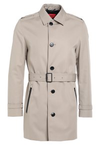 Trench coat beige con chiusura a bottoni, vita con cintura, due tasche laterali con zip e colletto classico. Tessuto morbido e vestibilità su misura.