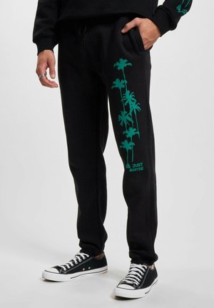 Black sweatpants with turquoise palm tree graphic along the left leg and "JUST RHYSE" text. Made of soft material, featuring an elastic waistband.