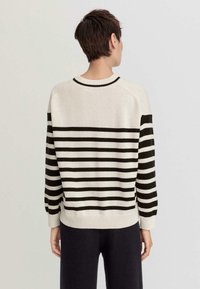 Strickpullover mit schwarzen und cremefarbenen horizontalen Streifen, Rundhalsausschnitt, gerippte Ärmelbündchen und Saum. Weiche Textur, lockerer Schnitt, Raglanärmel.