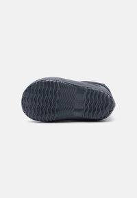 Semelle de sneaker bleu foncé avec un motif en zigzag texturé, en caoutchouc. Montre des rainures pour l'adhérence et une zone lisse pour le soutien.