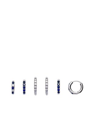 Six petites boucles d'oreilles en argent en forme de créoles, ornées de pierres précieuses bleues et transparentes alternées, vues de face et de profil sur un fond blanc.