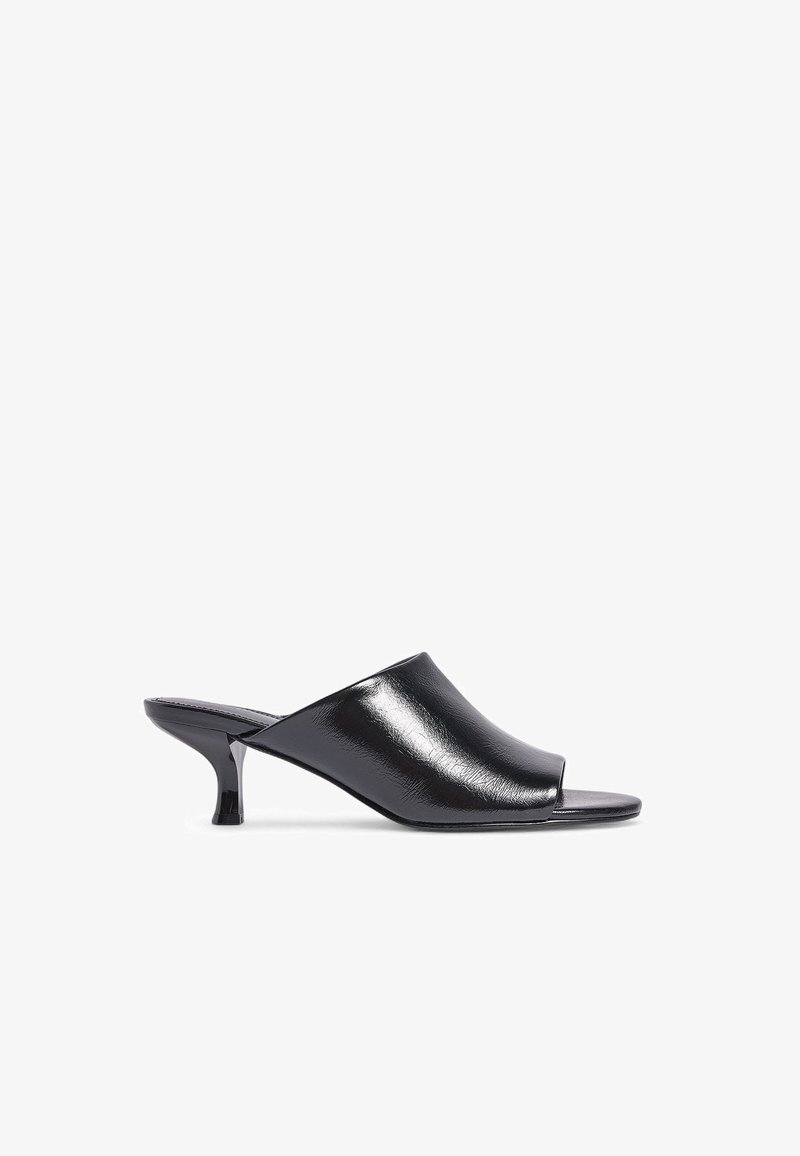 Mules negras de punta abierta elaboradas en material sintético brillante, con un diseño minimalista y un tacón delgado en forma de cono.