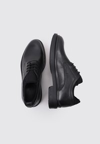 Chaussures en cuir noir avec une finition lisse, bout arrondi, design à lacets et accents texturés sur le côté.