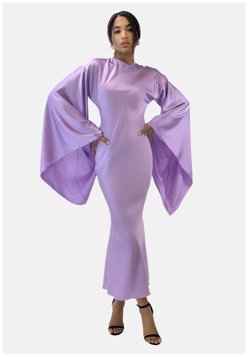 Abito di raso lilla con maniche lunghe e ampie, scollo alto e silhouette aderente che si allarga all'orlo. Indossato con sandali neri con cinturini.