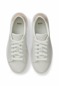 Hvide lædersneakers med en glat overflade, der har runde snørebånd, en beige ruskinds-hælaccent og prægede branding på tungen.