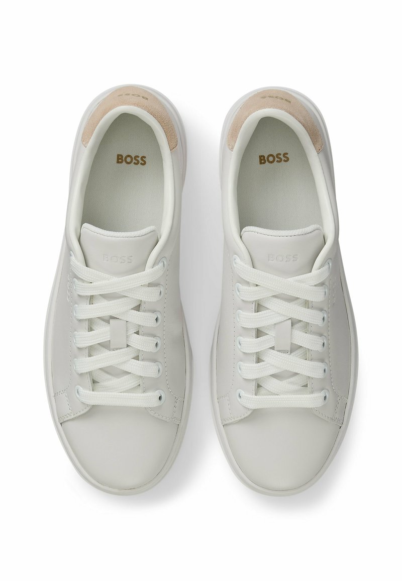 Baskets blanches en cuir à la finition lisse, avec des lacets ronds, un accent de talon en daim beige et un logo en relief sur la languette.